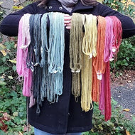 Person holding colorful scarves outdoors with trees and leaves in the background